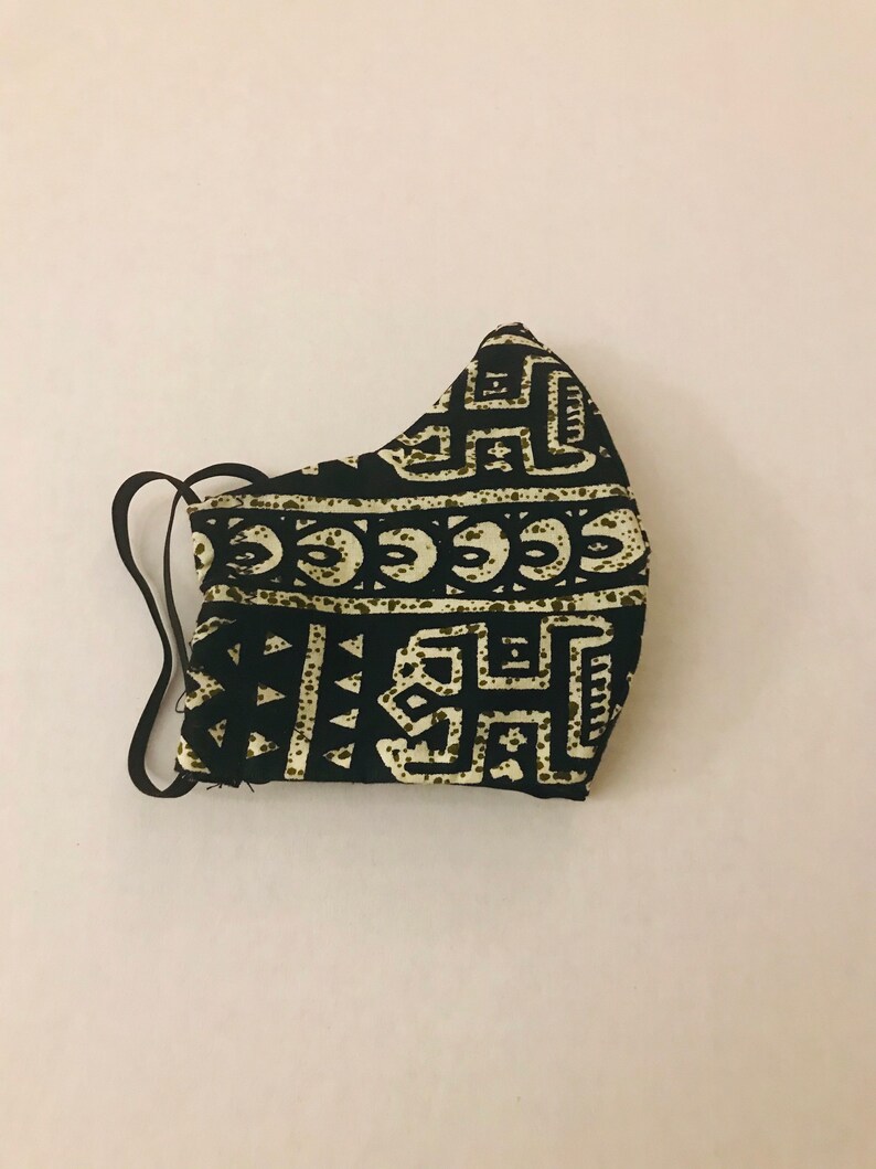 May include: Black and white face mask with a geometric pattern. The mask has a black elastic band.