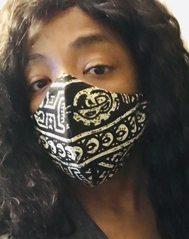 May include: A person wearing a black and white patterned face mask with geometric designs. The mask covers the nose and mouth.