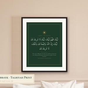 May include: A framed wall art print featuring a dark green background with white Arabic calligraphy and English translation text. The design includes a gold star emblem at the top and thin gold border lines, all encased in a black frame.