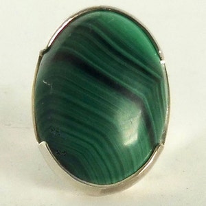 Könnte beinhalten: Ein Ring aus Silber mit einem grünen Malachit-Edelstein. Der ovale Stein hat ein wirbelndes Muster aus dunkelgrün und schwarz.