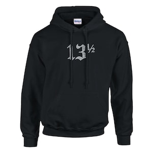 Può includere: Una felpa con cappuccio nera dotata di tasca a marsupio, maniche lunghe e cappuccio con coulisse. Al centro del petto è presente la scritta ricamata in bianco 13 1/2 in un carattere gotico stilizzato. Il capo include un'etichetta Gildan.