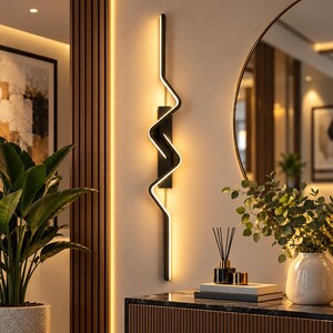 May include: A vertical wall-mounted LED light fixture featuring a black frame with a zigzagging, illuminated white light strip. The design consists of a central rectangular base plate with a continuous, angular light bar extending upwards and downwards.