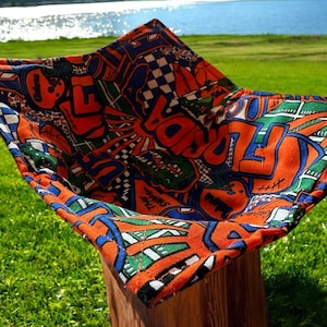 May include: Orange and blue fabric storage basket with a colorful graphic print featuring the word "Florida" and other designs. The basket is sitting on a wooden surface.