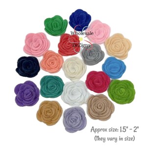 May include: A collection of felt rose embellishments in various colors including red, blue, pink, green, purple, and beige. The text Wholesale DeZigns is visible in the center, and the text Approx size: 1.5" - 2" (they vary in size) is at the bottom.