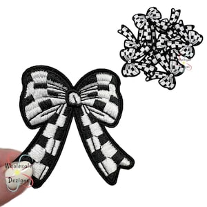 May include: Black and white checkered bow patches. The patches have a detailed embroidered design. The bow patches are a fun accessory for clothing, bags, or crafts. The image shows a single bow patch and a small pile of bow patches.