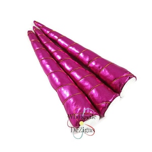 May include: Three conical unicorn horns in a vibrant metallic fuchsia pink finish. Each horn features a spiraling gold cord wrapped around the exterior from base to tip. The base of each horn is white. The text Wholesale DeZigns is visible.