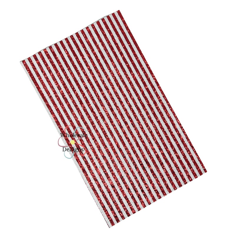 May include: A rectangular sheet of red and white striped glitter fabric. The stripes run diagonally across the surface. The fabric has a shiny, textured appearance. The image is against a white background. The product is from Wholesale Designs.