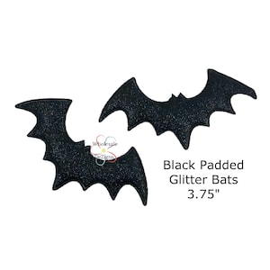 May include: Two black glitter bats with a padded texture. The bats are 3.75 inches in size.