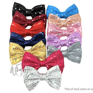 May include: A collection of sequined bow ties in various colors, including black, red, gold, and blue. The bows are arranged in a stack, showcasing their shimmering texture. The image also includes text that says "Wholesale" and "Out of stock colors on second image."