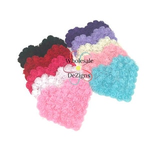 May include: A collection of heart-shaped fabric flower arrangements in various colors including black, red, pink, white, cream, lavender, dark purple, and turquoise. Each heart is composed of multiple small, layered fabric rosettes.
