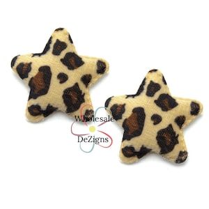 May include: Two star-shaped fabric embellishments with a tan background and brown leopard print spots. The stars are soft and plush, perfect for crafting or adding a unique touch to accessories. The image also includes the text "Wholesale DeZigns".