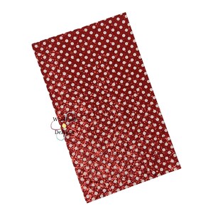 May include: A rectangular sheet of red glitter fabric with a white polka dot pattern. The fabric has a shiny, textured surface and is angled slightly. Suitable for crafts and DIY projects.