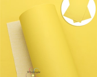 May include: A roll of bright yellow faux leather with a textured surface. The leather is rolled up and has a white backing. The image also shows a close-up of a piece of the leather.
