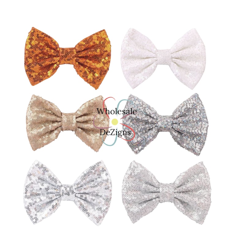 May include: A set of six bow-shaped hair accessories covered in shimmering sequins. The bows are arranged in two columns and three rows, featuring colors of copper, white, champagne, silver, and light gray. The text Wholesale DeZigns is visible.