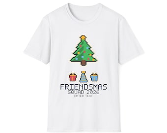 Puede incluir: Una camiseta blanca de manga corta con un gráfico de arte de píxeles de un árbol de Navidad, tres pequeños regalos y el texto "FRIENDSMAS SQUAD 2026 ENTER TEXT" impreso en una fuente de píxeles negra centrada en la prenda.