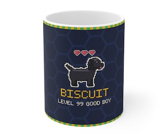 Puede incluir: Una taza de cerámica azul oscuro con un perro negro en pixel art, tres corazones rojos y el texto amarillo BISCUIT LEVEL 99 GOOD BOY. La taza tiene un fondo de patrón de panal azul oscuro y un borde a rayas verde y amarillo arriba y abajo.
