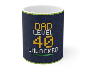 Puede incluir: Una taza de cerámica blanca con un fondo de patrón hexagonal azul oscuro. El frente presenta texto pixelado en amarillo y blanco que dice DAD LEVEL 40 UNLOCKED, con una barra de progreso verde en la parte inferior y borde amarillo y verde.
