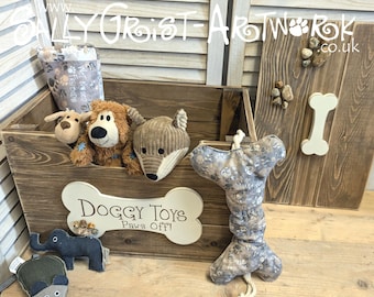 Peut inclure: Une caisse de rangement en bois brun foncé avec une plaque en forme d'os couleur crème portant l'inscription "Doggy Toys Paws Off!" et un couvercle assorti. La caisse contient des peluches et un jouet en tissu en forme d'os à motifs de pattes.