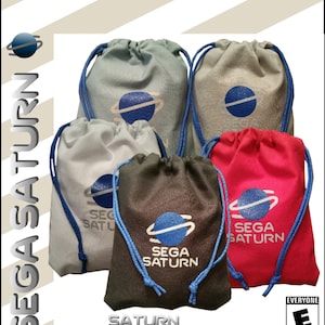 Puede incluir: Bolsas para mandos de Sega Saturn en varios colores: gris, gris claro, gris oscuro y rojo. Cada bolsa presenta un gráfico de Saturno azul y blanco y las palabras "SEGA SATURN". Las bolsas tienen cordones azules.