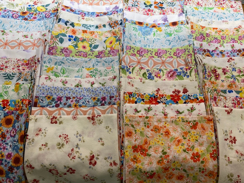 May include: A collection of fabric squares with various floral patterns in shades of pink, blue, green, yellow, and orange. The fabric squares are arranged in rows and columns, creating a visually appealing display.