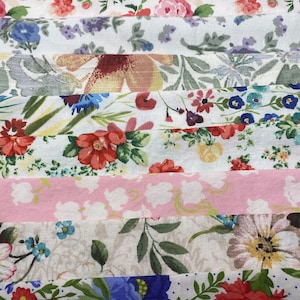May include: A collection of 10 fabric strips with various floral patterns. The fabrics are in shades of pink, white, green, blue, and red. The patterns include small and large flowers, leaves, and dots.