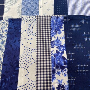 May include: A patchwork quilt with various blue and white patterns, including floral, geometric, and paisley designs. The quilt is made of different fabrics and textures, creating a unique and interesting look.