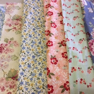 May include: Five different fabric swatches with floral patterns. The fabrics are in various colors, including blue, pink, green, and white.