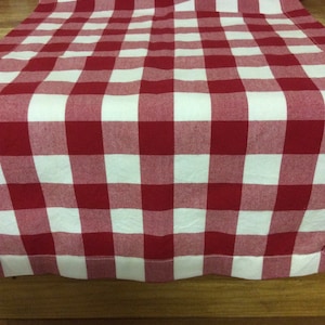 May include: Red and white checkered table runner. The runner is made of a woven fabric and has a simple, classic design.