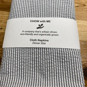 May include: Gray and white striped cloth napkins with the text "CHOW with ME" and "A company that's artisan driven, eco-friendly and organically grown. Cloth Napkins Dinner Size" on a white label.