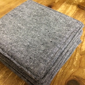 May include: A stack of gray fabric squares with a textured surface. The fabric is folded neatly and has a subtle sheen.