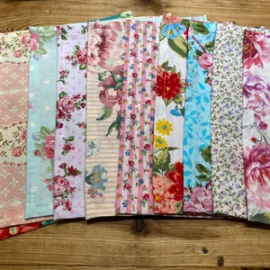 May include: A collection of 10 fabric swatches with floral patterns in shades of pink, blue, and white. The fabrics have a variety of textures, including gingham, stripes, and polka dots.
