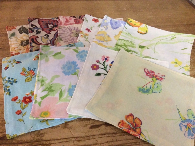May include: A set of ten fabric napkins with floral patterns in various colors, including pink, blue, green, yellow, and white.
