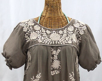 May include: A gray embroidered blouse with white floral embroidery. The blouse has short sleeves and a gathered neckline.