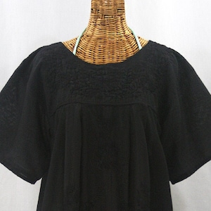 May include: A black, short-sleeved, embroidered blouse with a round neckline. The blouse is made of a lightweight fabric and has a loose, flowing fit.