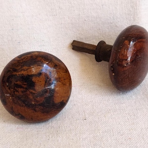 May include: Two brown ceramic door knobs with a marbled pattern. The knobs have a metal stem for attaching to a door.