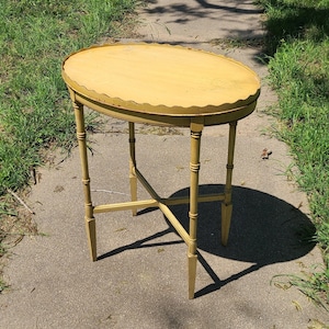 May include: A yellow oval-shaped side table with a scalloped edge and a four-legged base.