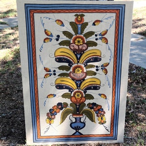 May include: A vintage style tea towel with a floral design in shades of yellow, blue, orange, and red. The design features a stylized flower with a vase at the bottom.