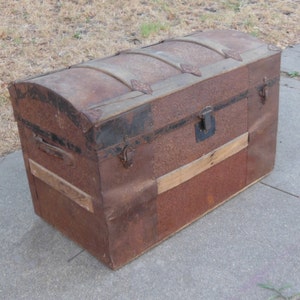 May include: A vintage, rusty metal trunk with a wooden top and metal accents. The trunk has a hinged lid and a lock.