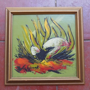 May include: Abstract painting in a gold frame. The artwork features a central white and silver form with yellow and green spiky shapes against a green background. Bold strokes of red and orange are at the bottom. The artist's signature, "Ashbrook," is visible.