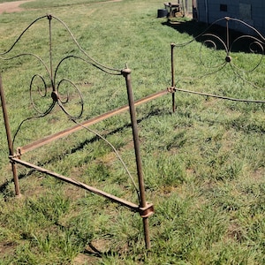 May include: A vintage metal bed frame with a scrolled headboard and footboard. The frame is made of wrought iron and has a rustic, aged look.