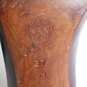 May include: Close-up of the sole of a brown leather shoe with the Gucci logo and the size 37 stamped on the bottom.