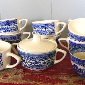 May include: A set of blue and white patterned ceramic teacups and a creamer. The cups have a blue and white floral design with a white background. The creamer is a white ceramic pitcher with a blue and white floral design.