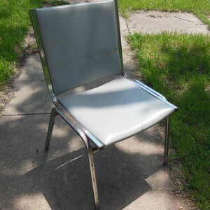 May include: A gray metal chair with a chrome frame. The chair has a padded seat and back.