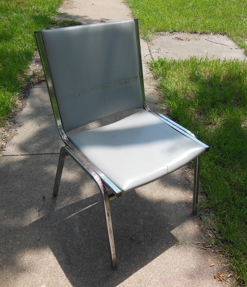 May include: A gray metal chair with a chrome frame. The chair has a padded seat and back.