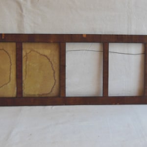 May include: A long, rectangular wooden picture frame with four separate openings. The frame is dark brown with a lighter brown wood trim. The openings are empty and have a light brown background.