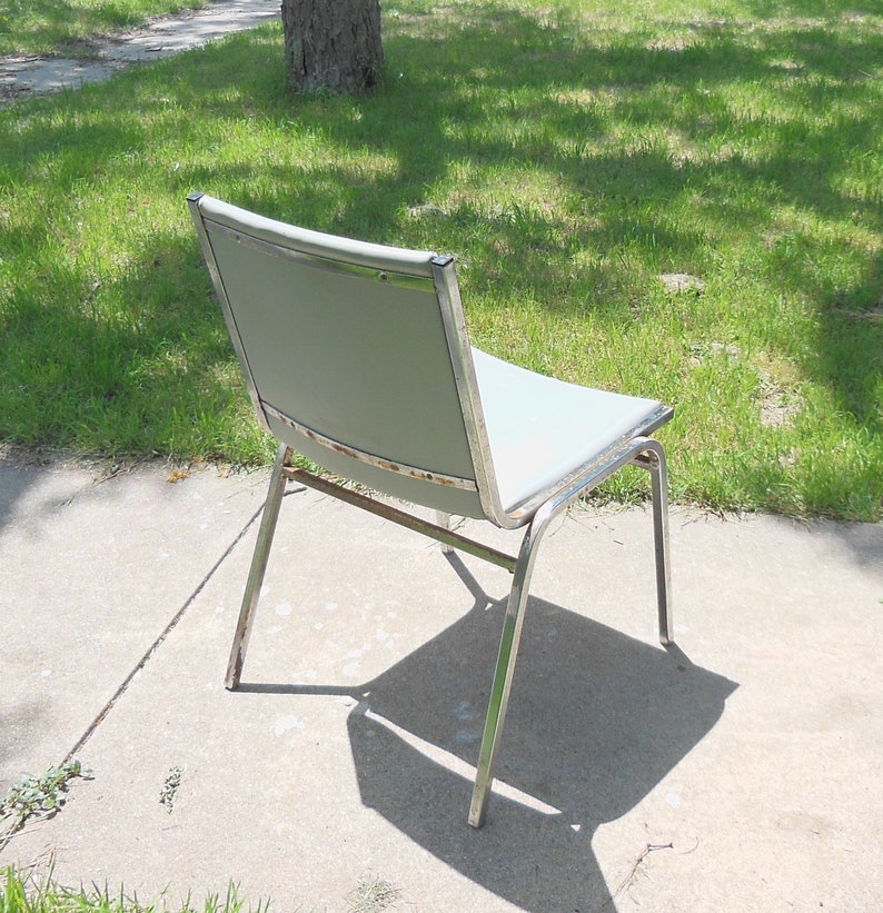 May include: A silver metal chair with a light gray fabric seat. The chair is sitting on a concrete patio.