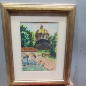 May include: A framed watercolor painting depicting a building with a golden dome, surrounded by trees and a small pond. Two figures are standing near the pond, and the painting is signed in the bottom left corner.