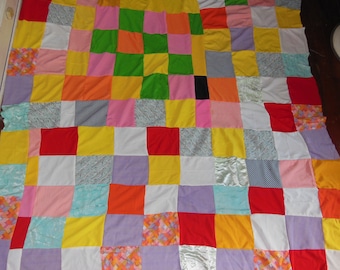 May include: A patchwork quilt made of various colored squares, including red, yellow, orange, green, blue, purple, and white.
