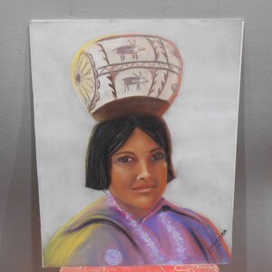 May include: A pastel drawing of a woman wearing a traditional Native American headdress. The headdress is a large, round, white pot with brown and black geometric designs. The woman has dark hair and brown eyes, and she is wearing a purple and yellow shawl.