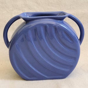 May include: A blue ceramic vase with two handles and a wavy design.